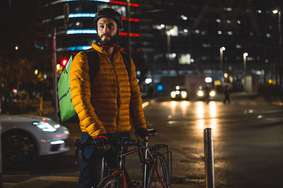 Man riding bicycle on street in city at night