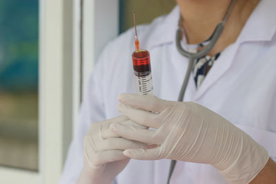 Midsection of doctor holding syringe