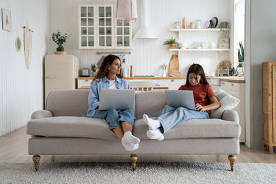 Young woman using digital tablet while sitting on sofa at home