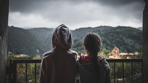 Rear view of people looking at mountains against sky