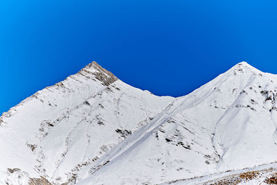 Scenic view of snowcapped mountains against clear blue sky