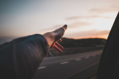 Close-up of hand leaning from window