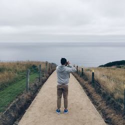 Rear view of man standing on beach against sky