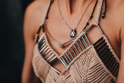 Part of a female body dressed in an elegant beige boho top with silver details. women's accessories