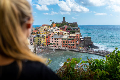 Woman by sea against sky in city