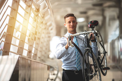 Handsome businessman holding bicycle covered walkway 