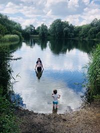 Rear view of people in lake against sky