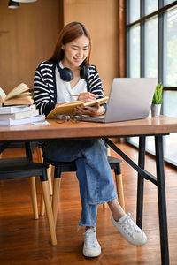 Young woman using laptop while sitting on table