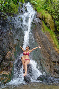 Rear view of man jumping in waterfall