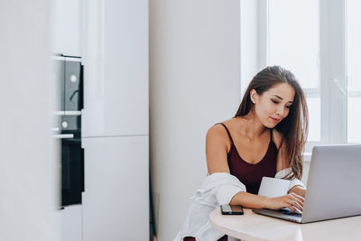 Young woman using phone while sitting on table