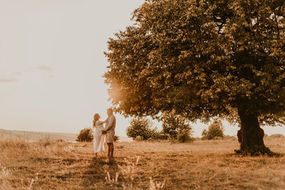 Rear view of woman walking on field against clear sky