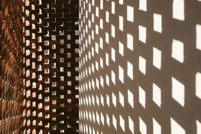Sunlight penetrating a perforated brick wall creating an abstract pattern of light and shadow