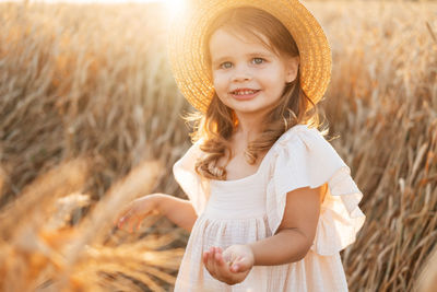 Portrait of young woman wearing hat standing on field