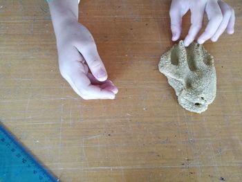 Cropped hand of child playing with clay on table