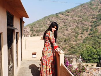 Woman standing by tree against mountain