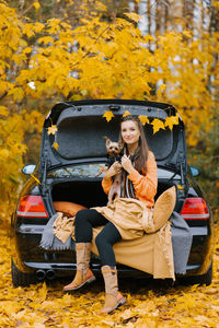 A young beautiful woman holds her beloved pet in the open air against the background of an autumn 