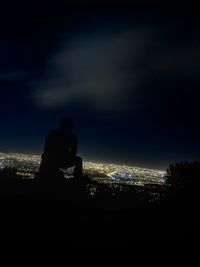 Silhouette cityscape against sky at night