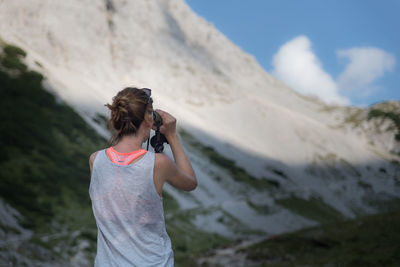 Rear view of woman standing on mountain against sky