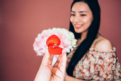 Cropped hand of man proposing woman against brown background