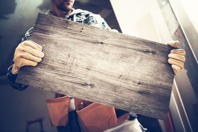 Midsection of man holding wood at home