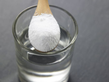 Close-up of powdered sugar with water in drinking glass on table