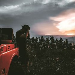 Man standing on field against sky during sunset