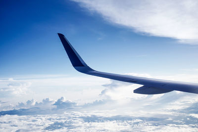 Airplane flying over clouds against blue sky