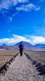 Rear view of man walking on desert against mountain