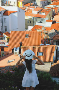 Rear view of woman standing against buildings in city