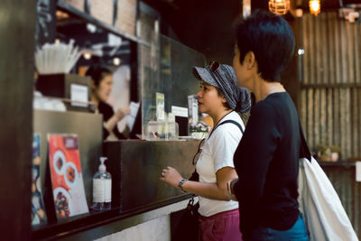 Two women friends placing an order to take out in a coffee shop.