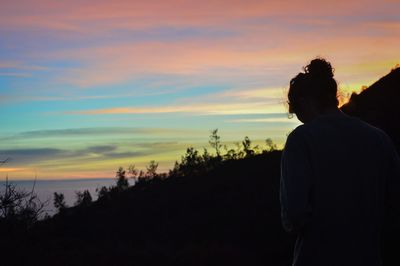 Rear view of silhouette man standing against orange sky