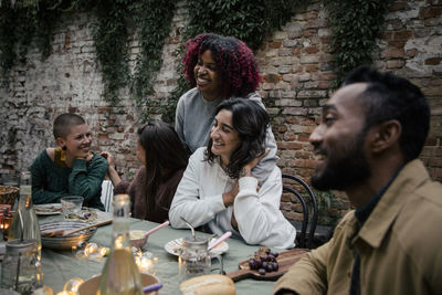 Smiling multiracial male and female friends talking with each other during dinner party