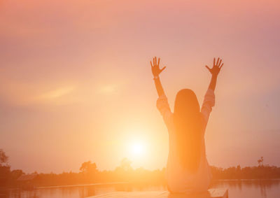 Rear view of silhouette woman standing against sky during sunset