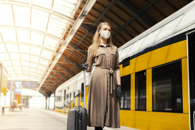 Low angle view of woman wearing mask standing at railroad station