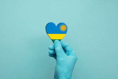 Close-up of hand holding heart shape against blue background