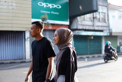 Side view of young woman standing in city