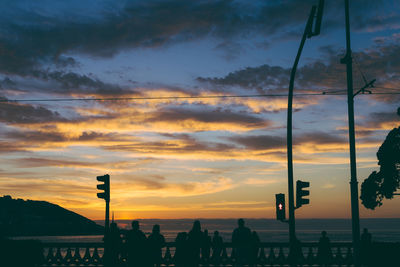 Silhouette street lights against orange sky