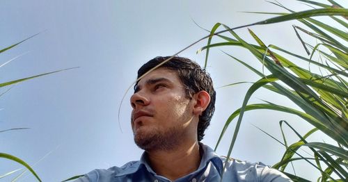 Low angle view of young man looking away against sky