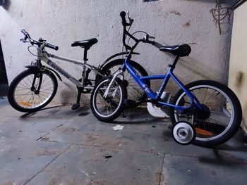 Bicycle parked on footpath against wall