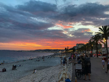 People on beach against sky during sunset