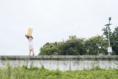 Rear view of person standing by plants against sky