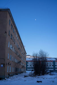 Snow covered buildings against blue sky