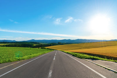 Road amidst field against sky