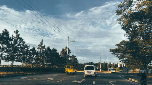 Cars on road against sky in city