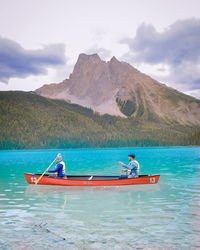 People in boat on lake against sky