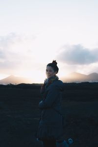 Woman standing on field against sky during sunset