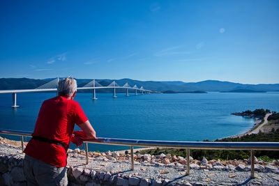 Rear view of senior man standing in front of peljesac bridge, croatia