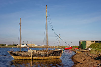 Sailboats moored on sea against sky