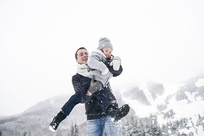 Father playing with daughter in winter landscape