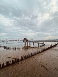 Wooden pier on beach against sky